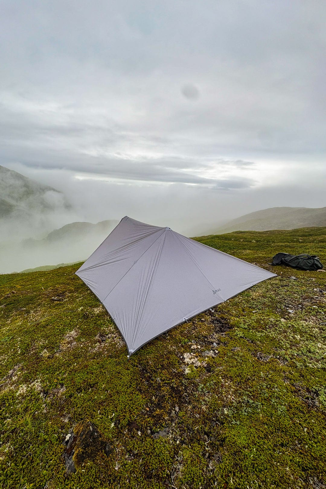 PEAX Equipment Solitude Hunting Tarp pitched on a mountain in Alaska with misty mountains in the background