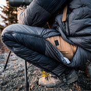 Pant side zipper opened as a hunter crouches behind a spotting scope