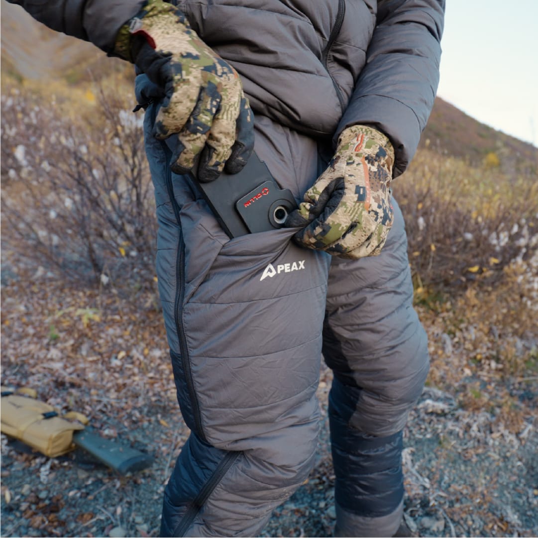 Gloved hunter sliding a rangefinder into the pant's zipper-free hand pocket