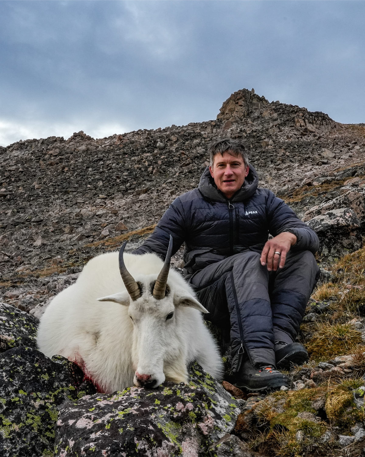 Hunter in the STATIC jacket and pant seated beside a harvested mountain goat