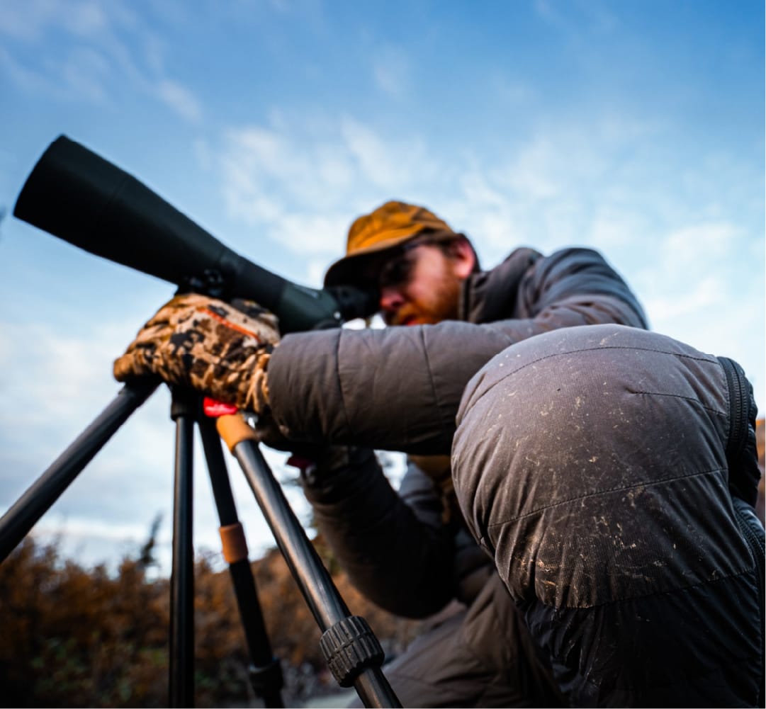 Frost-covered STATIC down jacket and pant on a hunter leaning into a spotting scope