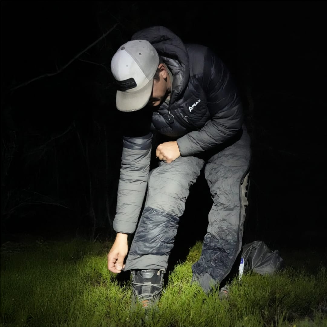 Hunter adjusting the pant cuff over a boot at night