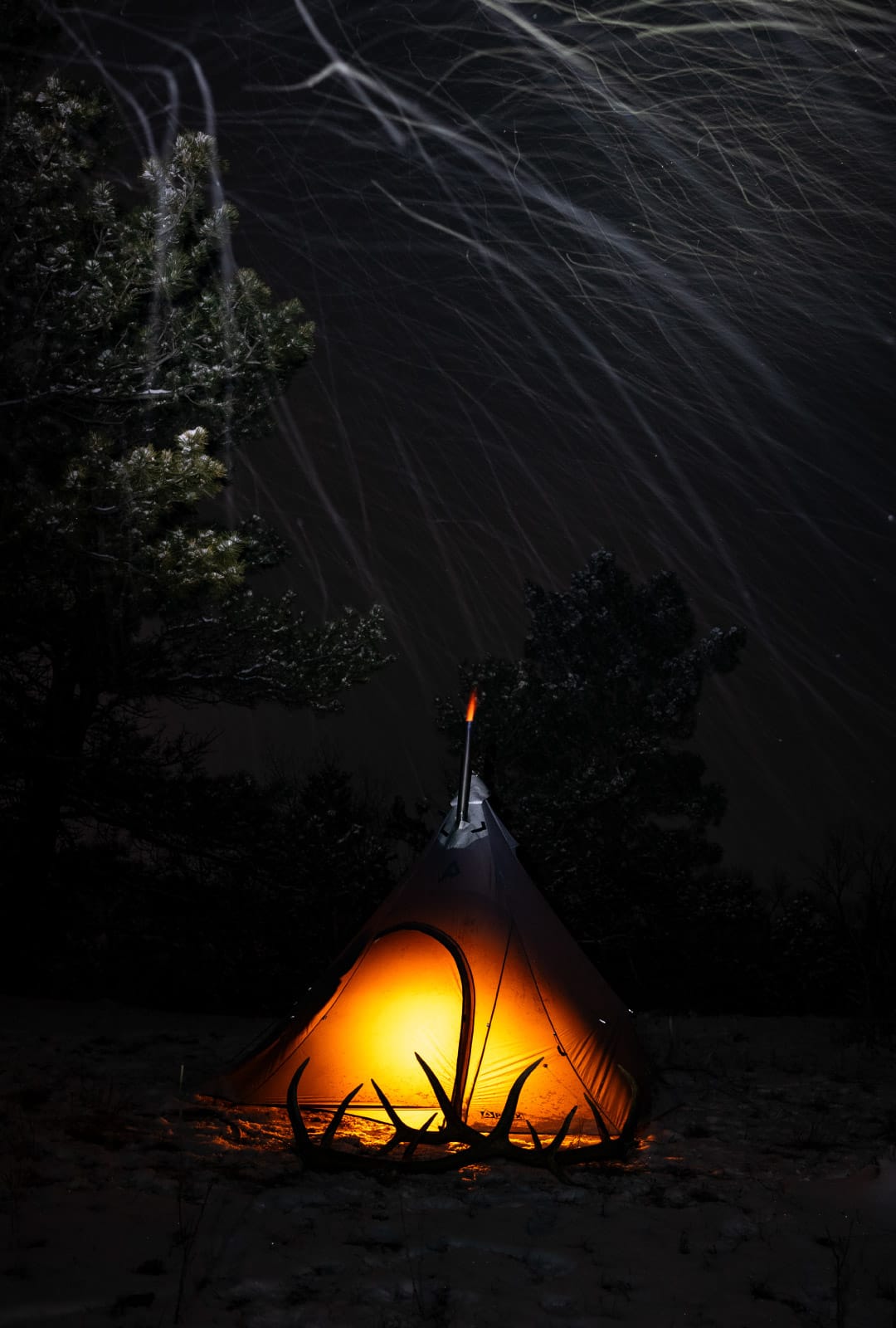 Solitude 4 Tipi Hot Tent with the Torrid backcountry titanium stove burning and some elk shed antlers in front of the tipi.
