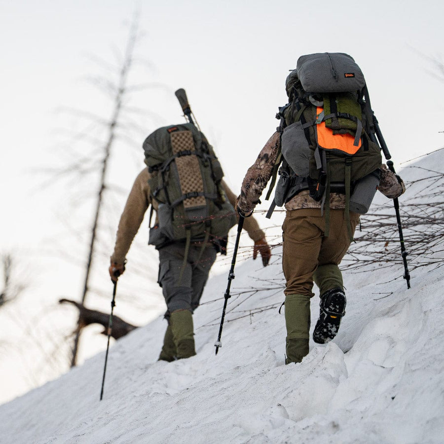 Hunters wearing PEAX Storm Castle gaiters while hiking through snow